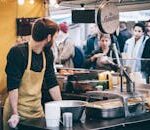 Dynamic scene of a street food vendor working in a busy market, engaging with diverse customers.